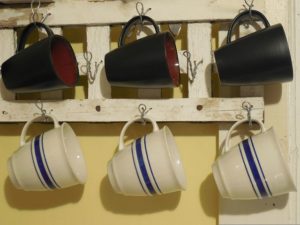 Schwarze und wei?e Cappuccinotassen h?ngen an der Wand 
